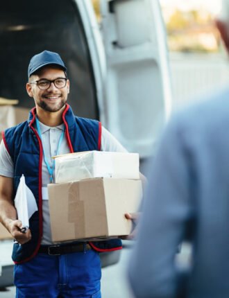 Happy,Deliverer,Carrying,Packages,While,Making,Home,Delivery,To,His